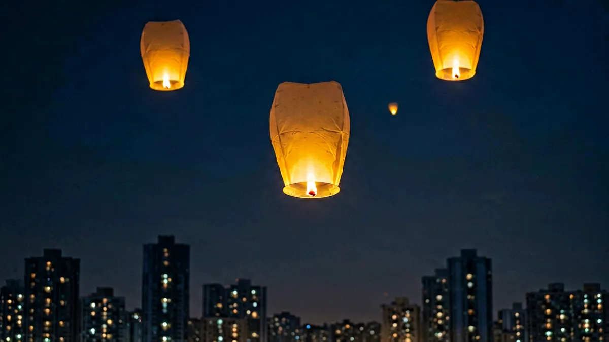 夜幕下孔明灯升空的剪影场景，远处城市轮廓隐约可见，灯笼的暖光映在深色天幕上，营造出浪漫却暗藏危险的氛围